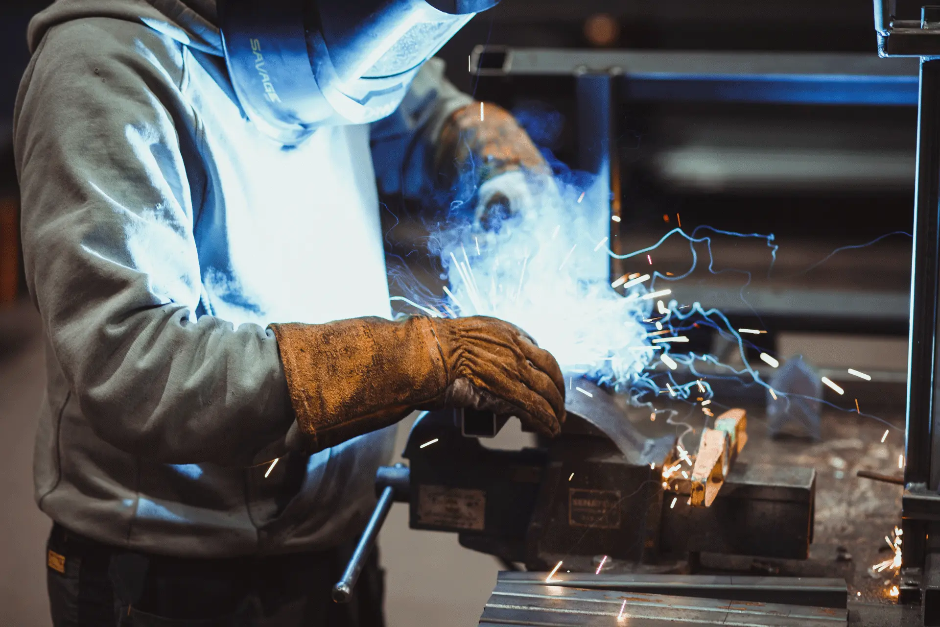 Welder working in a manufacturing facility with sparks showing industrial capability - visual content for manufacturers